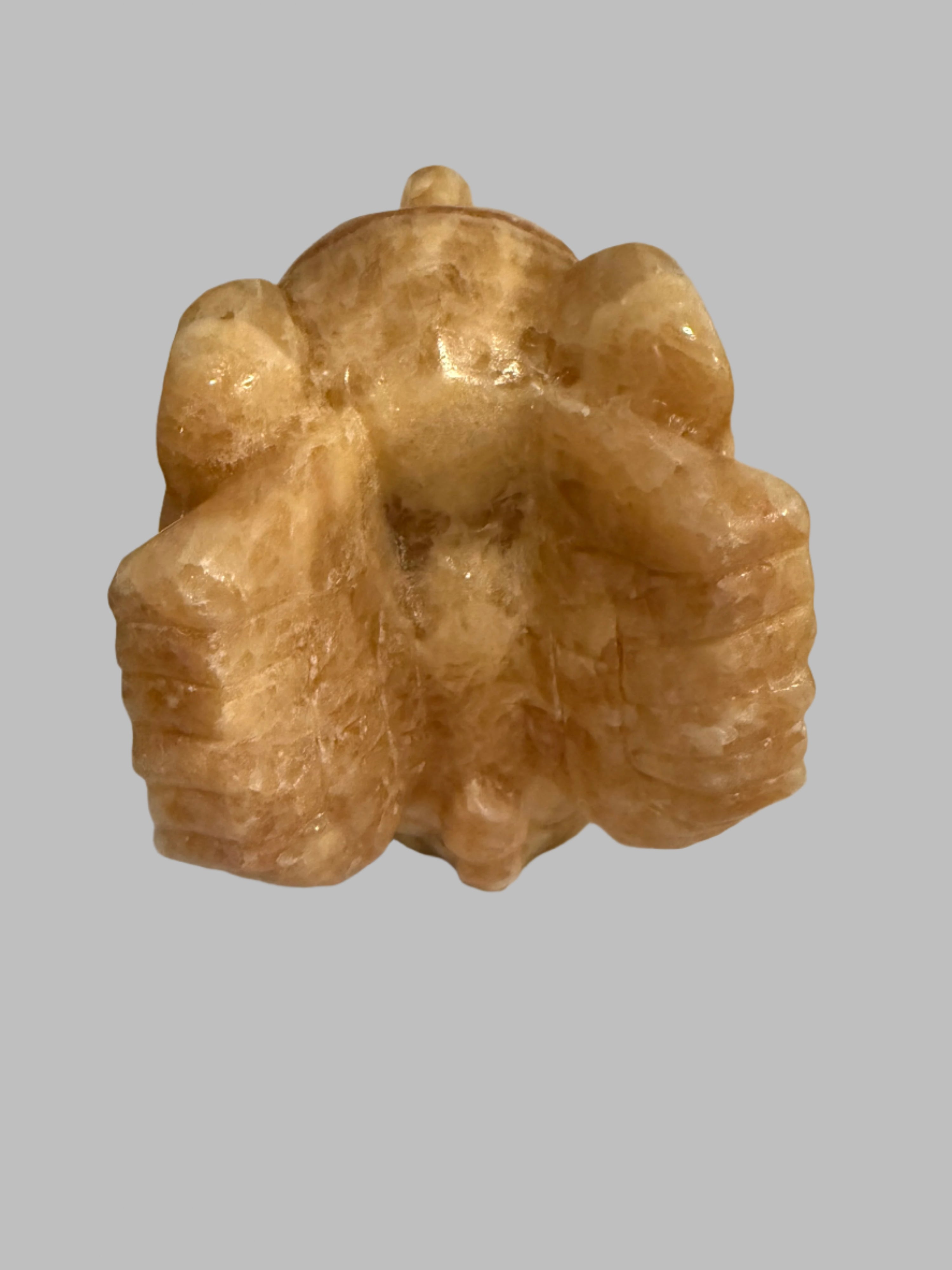 Brown stone sculpture of a seated figure on a plain background